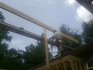 Carpenter setting a ridge beam over a new addition frame — Ice Dam Removal by Roofing Brothers in Pine Mountain