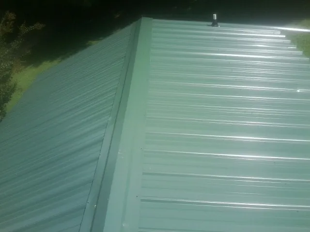 New green metal panels meeting at the ridge of a roof — Flat Roof Repair work by our crew in Pine Mountain
