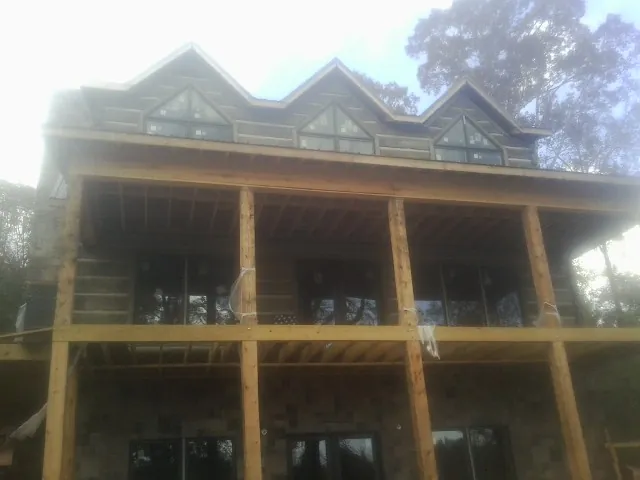 Dormers and porch framing on a large log home under construction — Roof Coating work by our crew in Pine Mountain