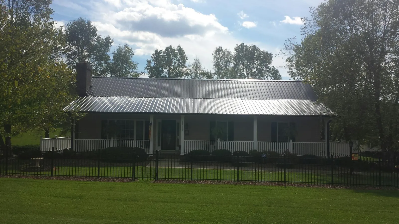 Gray metal roof on a brick ranch with a full width front porch — Gutter Guard Installation work by our crew in Pine Mountain