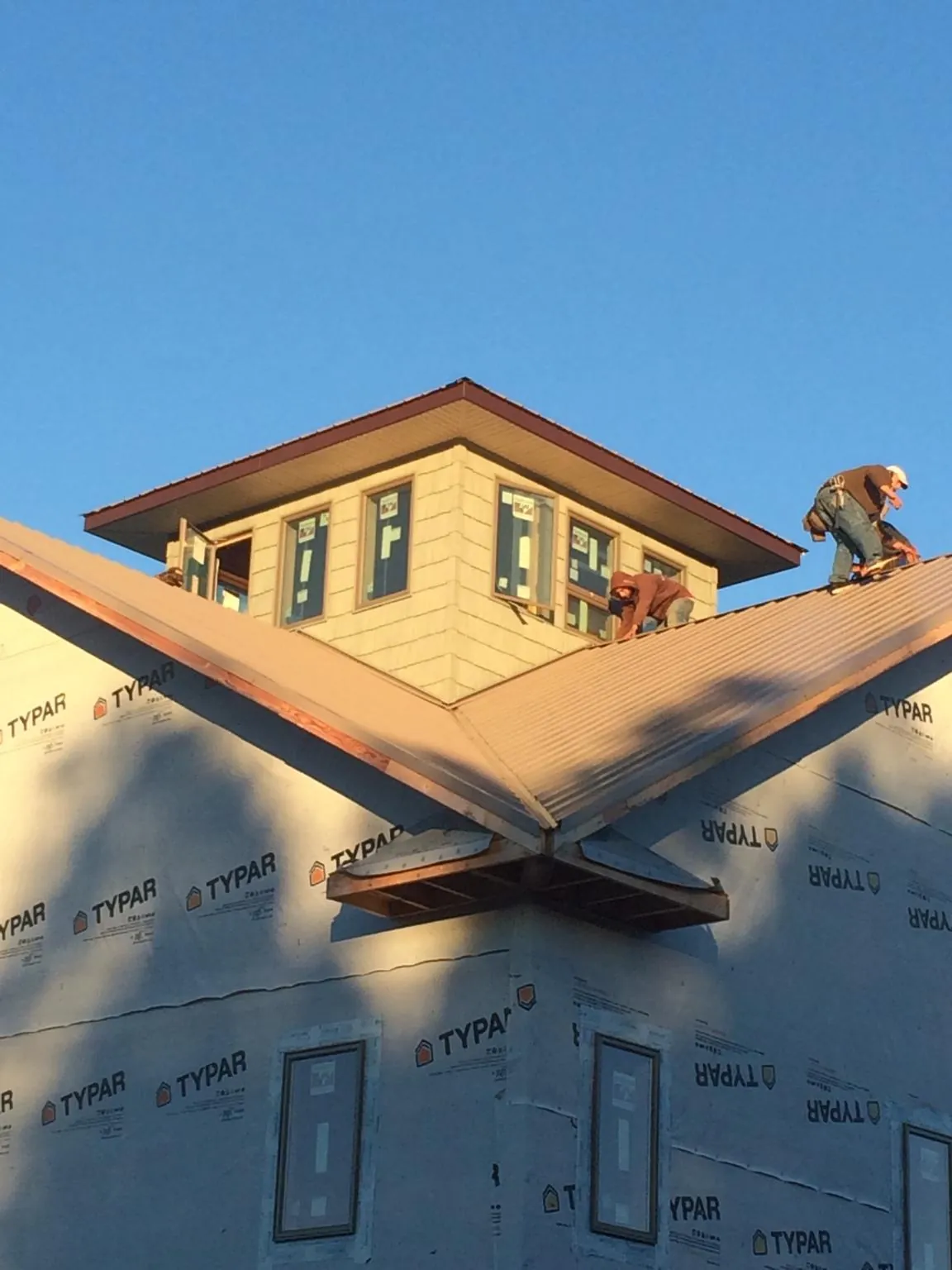 Roofers working around a rooftop cupola on a new metal roof at sunset — Roof Waterproofing in Pine Mountain by Roofing Brothers